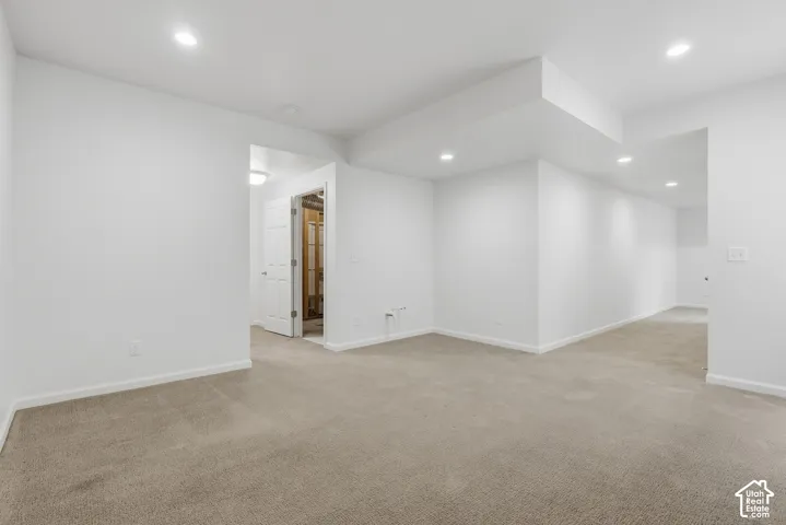 Carpeted flooring, recessed lighting, white walls, and a white door