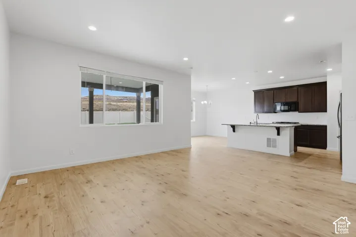Open-concept layout featuring wood-finish flooring, recessed lighting, and a kitchen island with seating