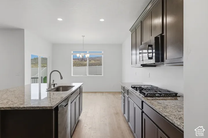 Kitchen featuring dark wood cabinetry, granite countertops, stainless steel sink with gooseneck faucet, built-in microwave, and gas cooktop