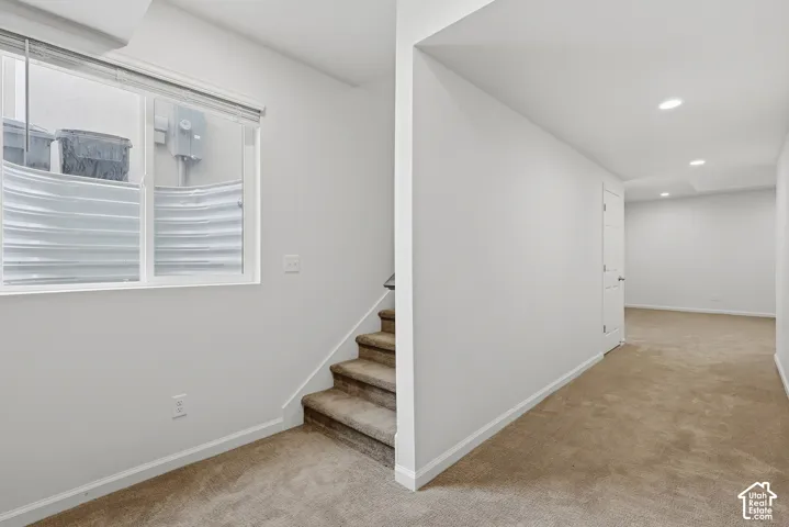 Carpeted stairs leading to a lower level with recessed lighting, carpeted flooring, and white walls