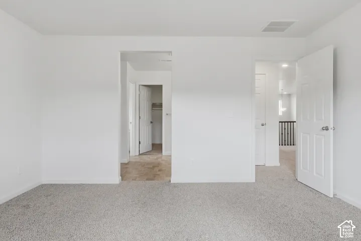 Carpeted flooring, white walls, white paneled doors, and a partial view of a staircase with wood railing