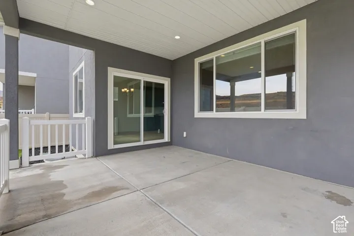 Covered concrete patio with white railing
