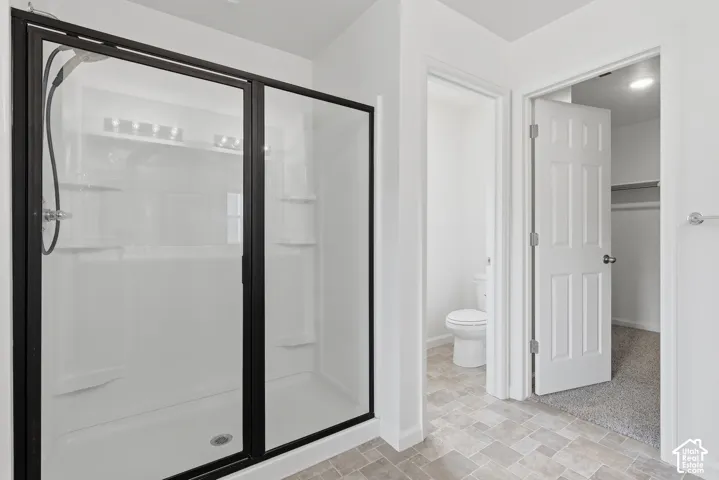 Shower with dark-framed sliding glass doors, built-in shelving, and white surround
