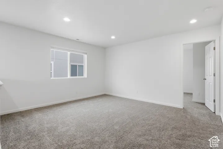 Recessed ceiling lighting, white interior walls, gray carpeting, white trim, and a window with blinds
