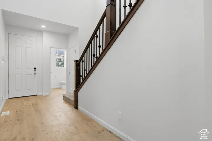 Wood-finish flooring, white paneled doors, recessed lighting, carpeted staircase, and dark wood handrail