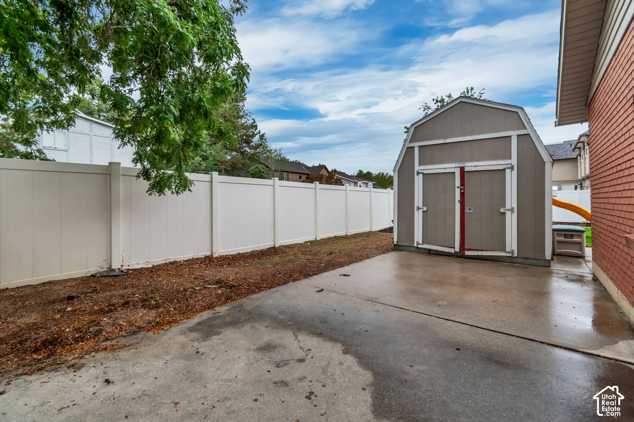 Concrete patio area, vinyl privacy fencing, and a barn-style storage shed