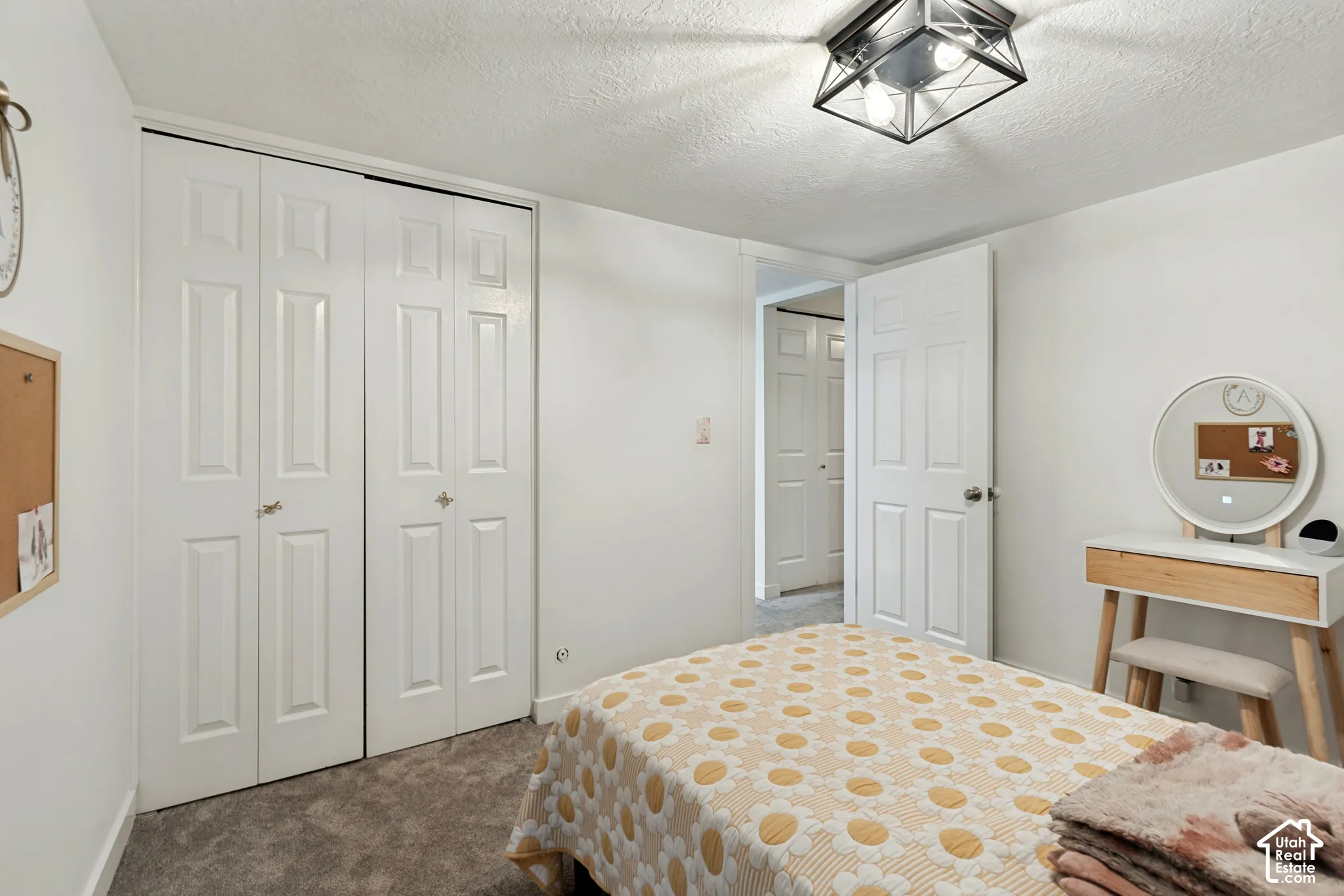 White paneled bi-fold closet doors, textured ceiling, and flush-mount ceiling light fixture