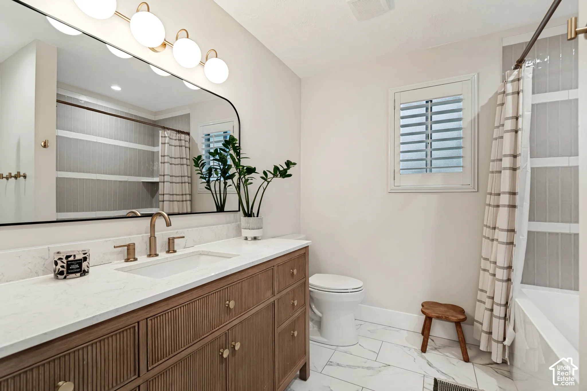 Wood-finish vanity with fluted detailing, white countertop, and gold-toned fixtures