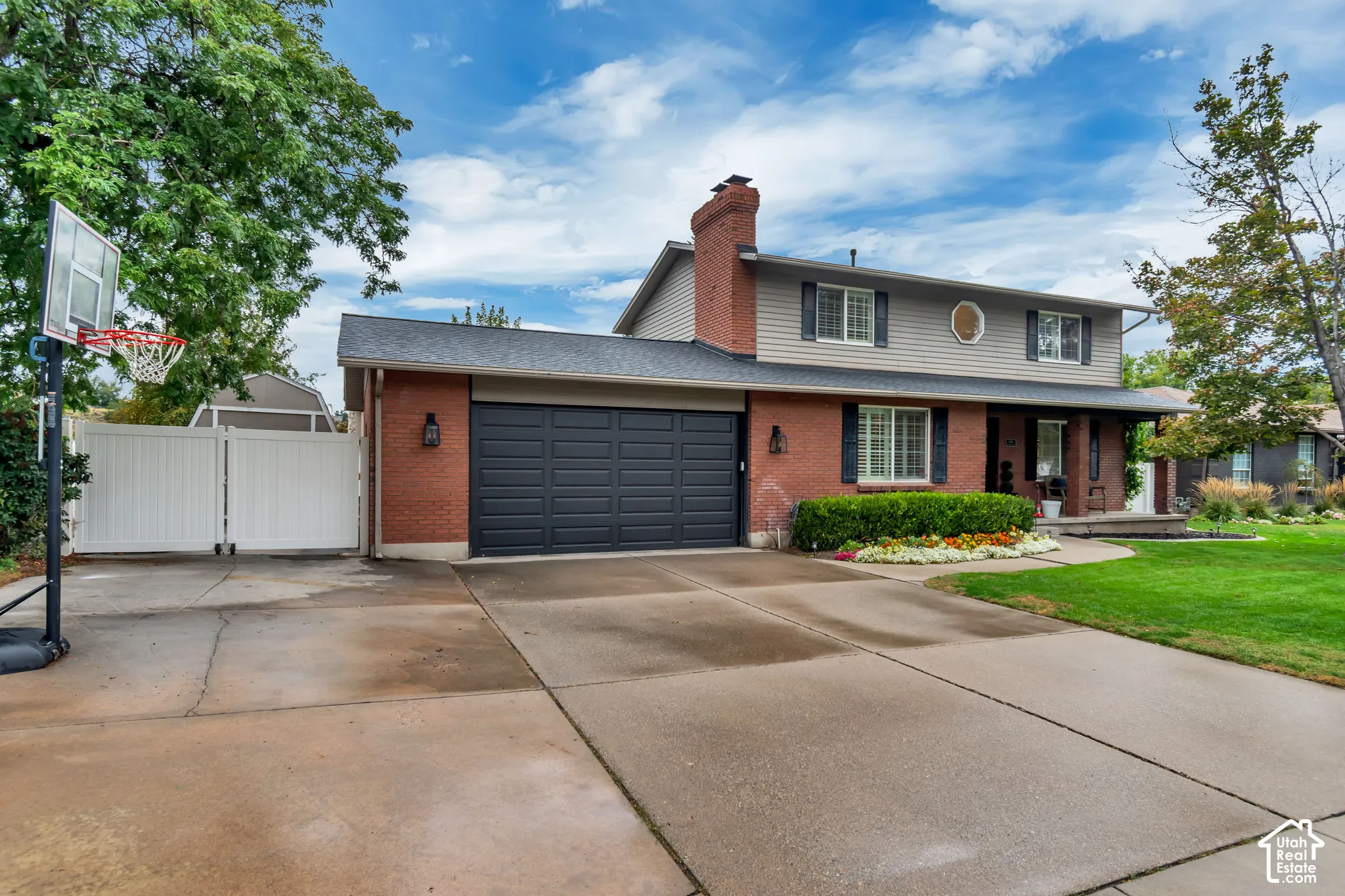 Brick and siding exterior with a two-car garage, mature landscaping, and a manicured lawn