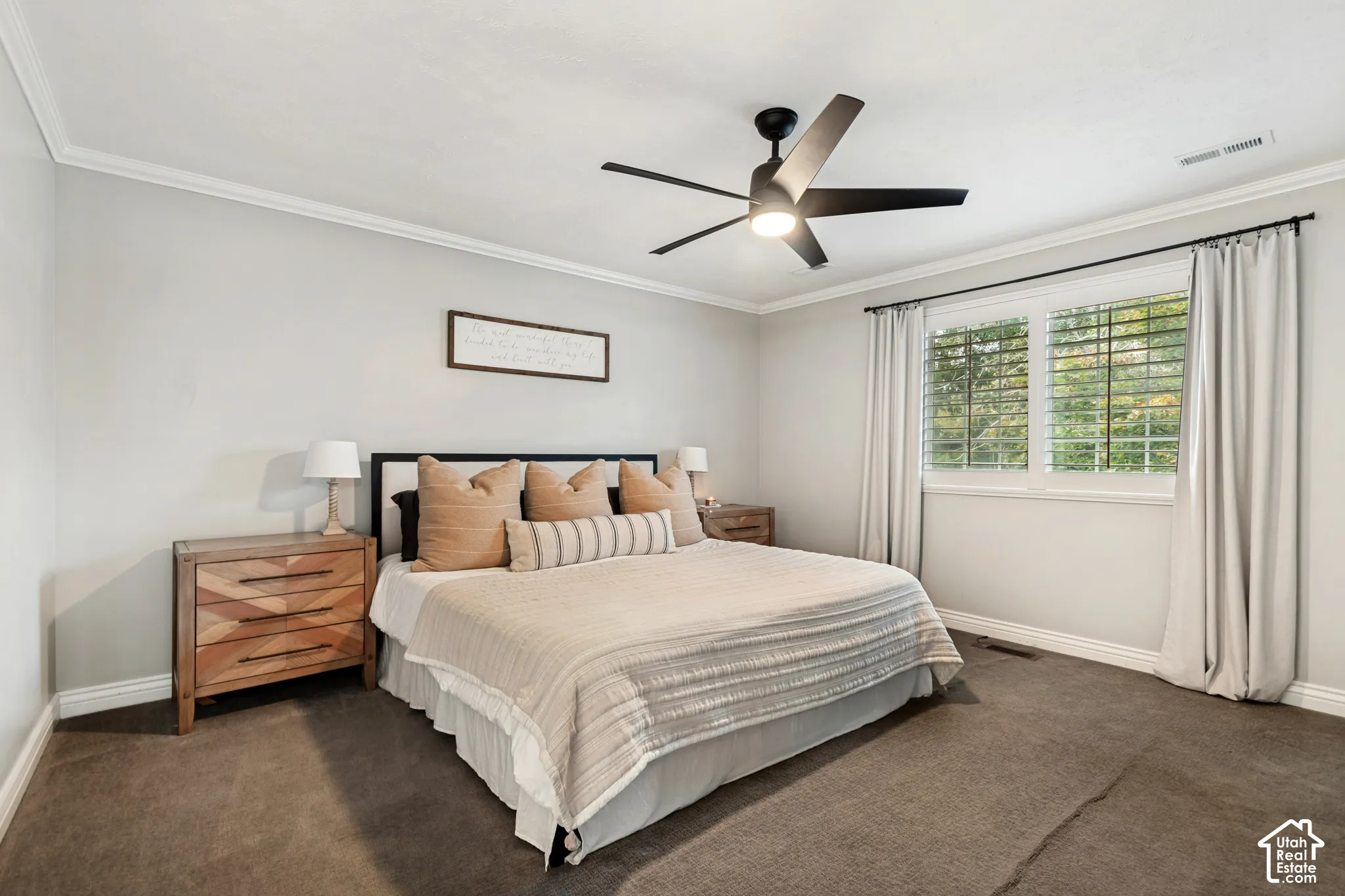 Recessed ceiling with crown molding, modern ceiling fan with integrated lighting, window with plantation shutters, broad window sill, and carpeted flooring