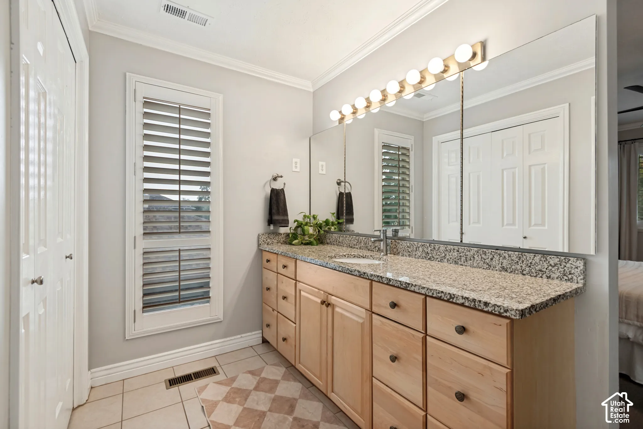 Double vanity with granite-style countertop, wood-finish cabinetry, and integrated sinks
