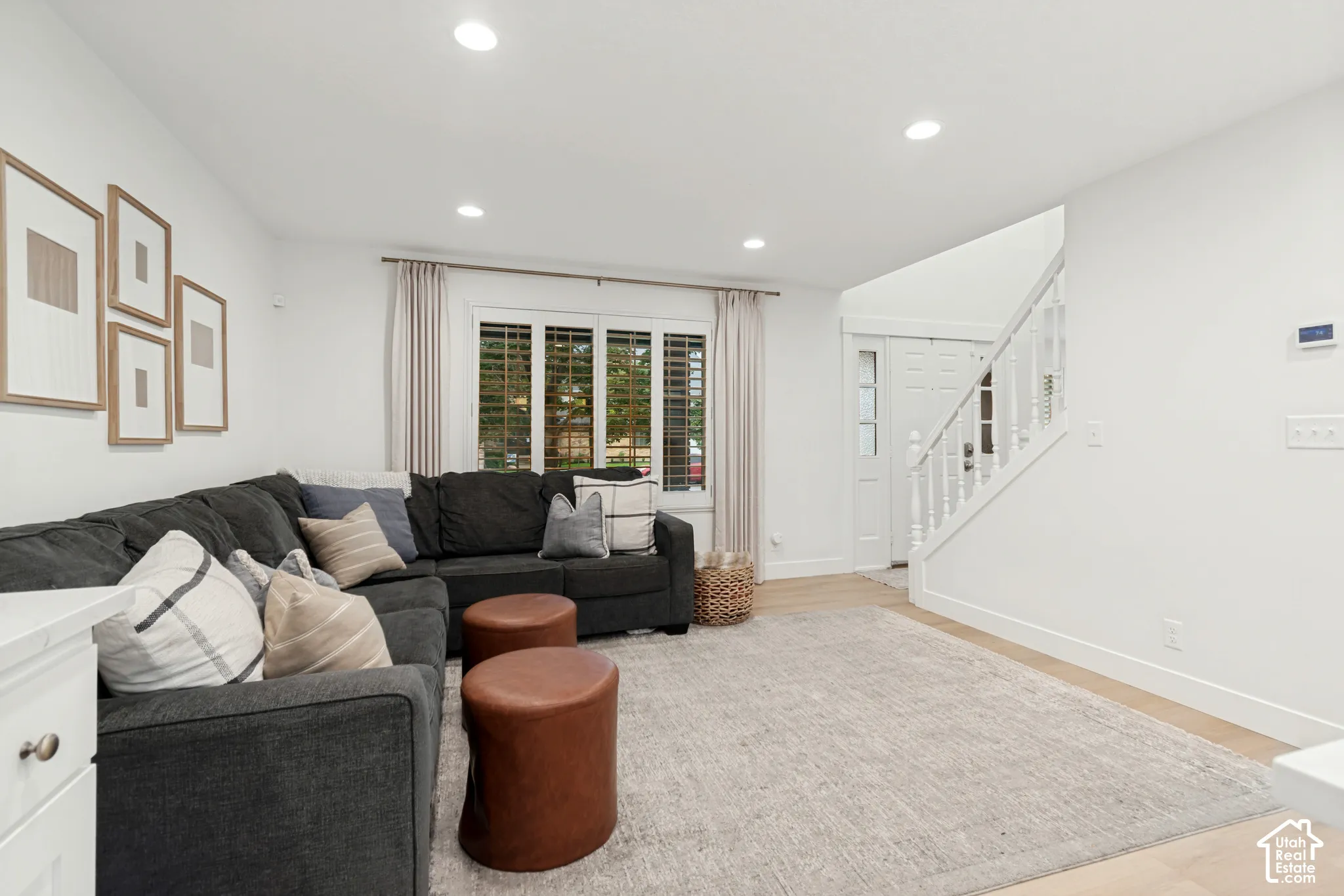 Recessed lighting illuminates the open-concept living space with light wood-finish flooring