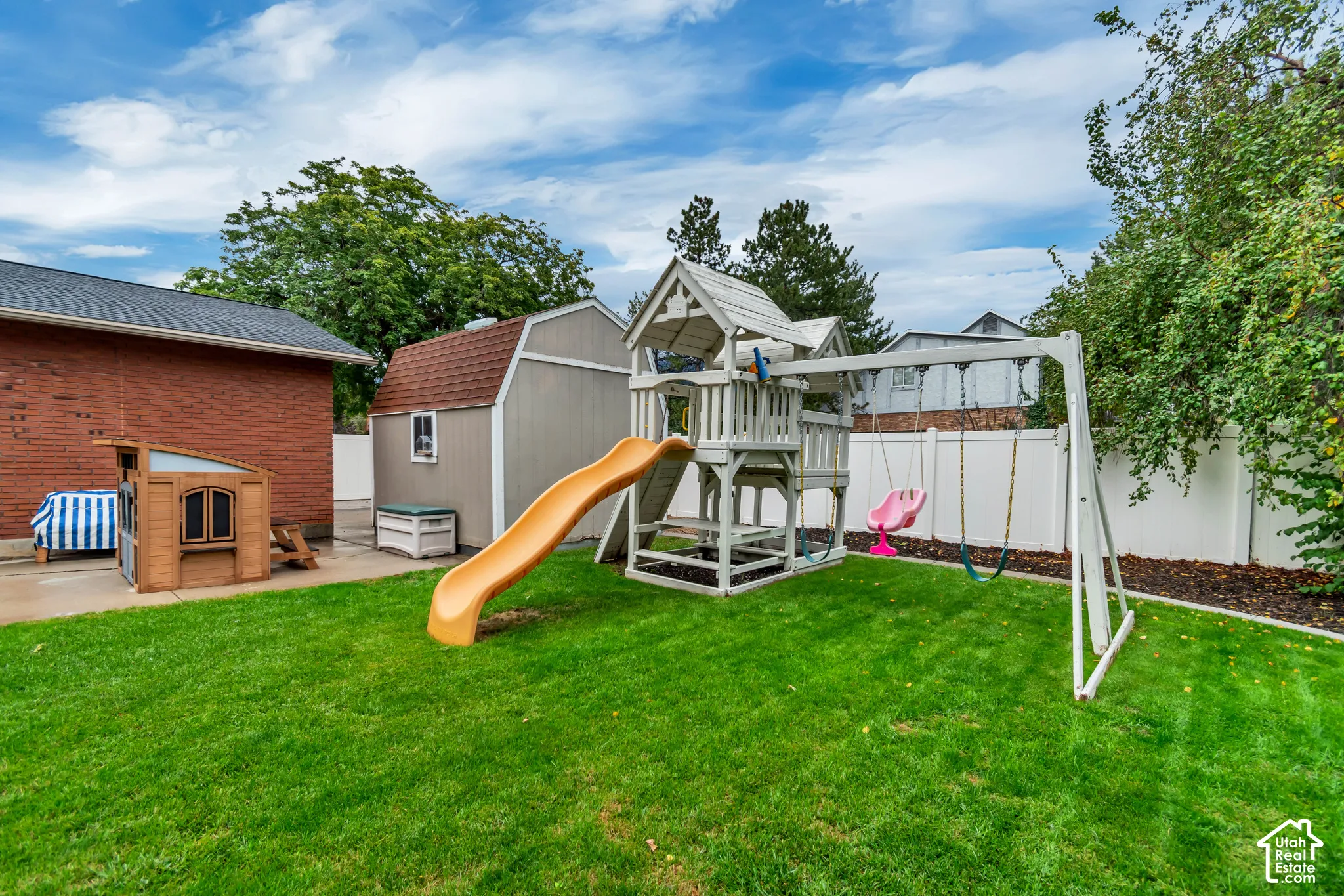 Expansive backyard featuring a lush lawn, vinyl privacy fencing, and a detached storage shed with a shingle roof