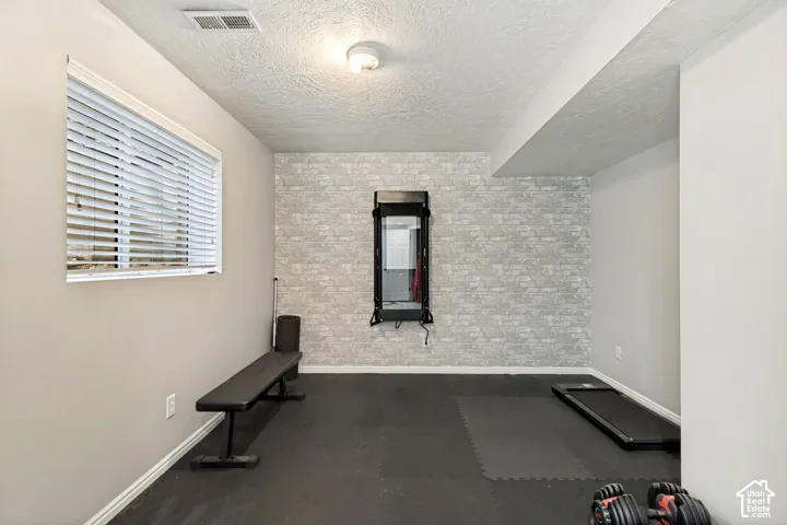 Recessed lighting illuminates the space, featuring a window with horizontal blinds and a textured accent wall