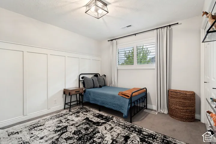 Board and batten accent wall, recessed window with louvered shutters, ceiling-mounted light fixture, and carpeting