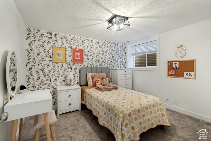 Accent wall with botanical print, window with blinds, ceiling-mounted light fixture, and carpeted flooring
