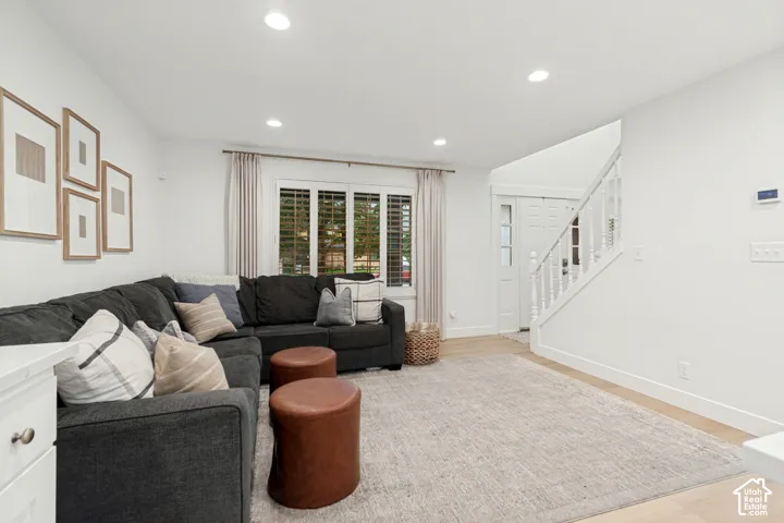 Recessed lighting illuminates the open-concept living space with light wood-finish flooring