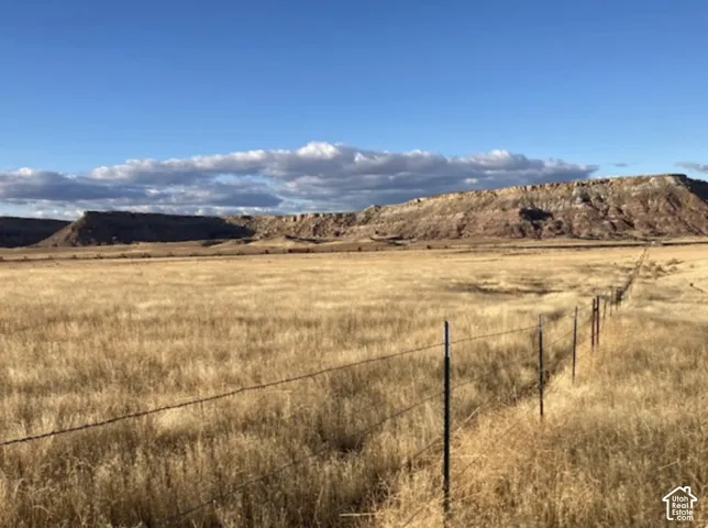 Expansive open land with a wire fence and distant natural rock formations under a clear sky
