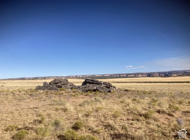 Expansive open terrain with natural rock formations, distant mesa, and clear sky