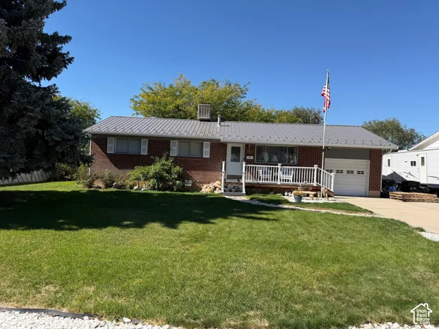 Brick exterior featuring a metal roof, front porch with white railing, and an attached garage