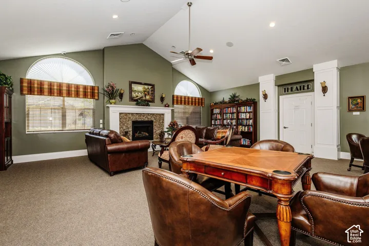 Vaulted ceiling with an integrated ceiling fan, fireplace with stone surround, recessed lighting, and arched transom windows