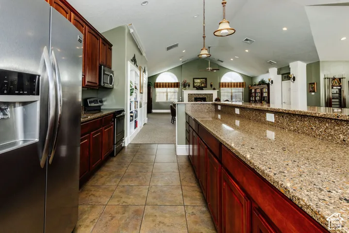 Stainless steel refrigerator, built-in microwave, tiled flooring, wood cabinetry, and granite countertops