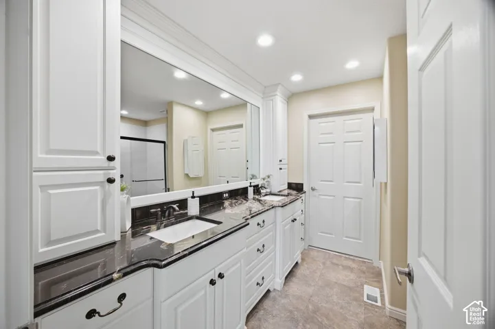 Double vanity with undermount sinks, dark countertops, and white cabinetry