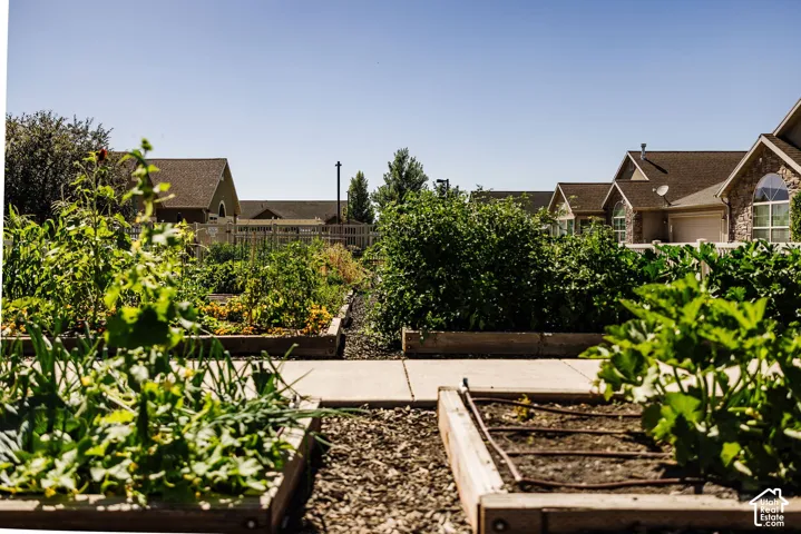 Raised garden beds with integrated irrigation system, mature plantings, and concrete pathways