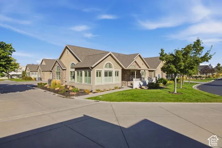 Stucco and stone exterior with arched windows, gabled roofline, and established landscaping