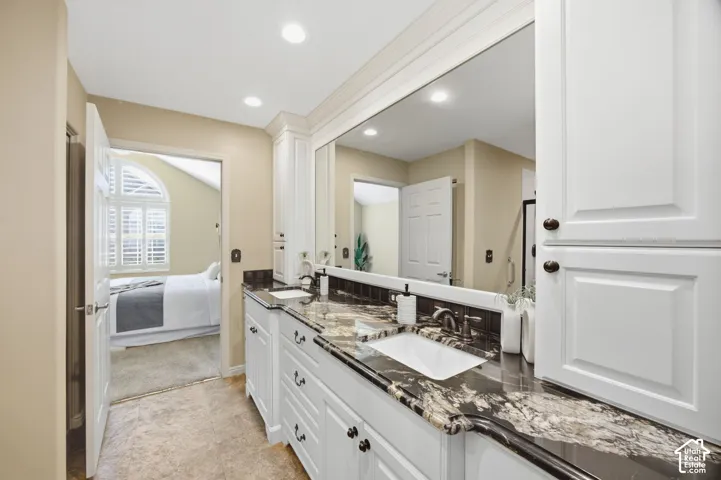 Dual vanity with solid surface countertops and integrated sinks, white cabinetry, and recessed lighting