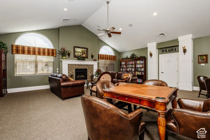 Vaulted ceiling, stone surround fireplace, arched windows, built-in shelving, and ceiling fan