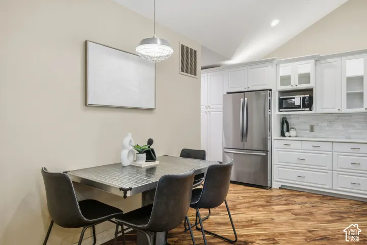 Kitchen featuring white cabinetry, stainless steel appliances, a tiled backsplash, and wood-finish flooring