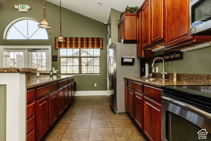 Kitchenette featuring wood cabinetry, speckled countertops, stainless steel appliances, and tile flooring