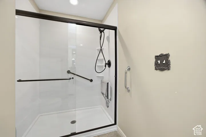 Glass-enclosed shower with dark bronze framing, an integrated shower seat, and multiple grab bars
