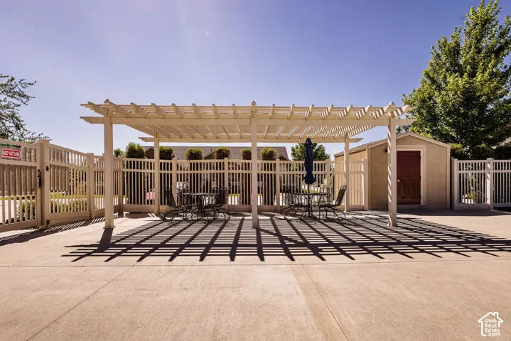 Expansive patio featuring a large pergola, privacy fencing, and a detached storage shed