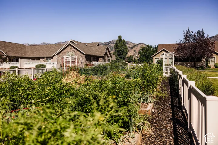 Community garden plots with a white picket fence and arbor