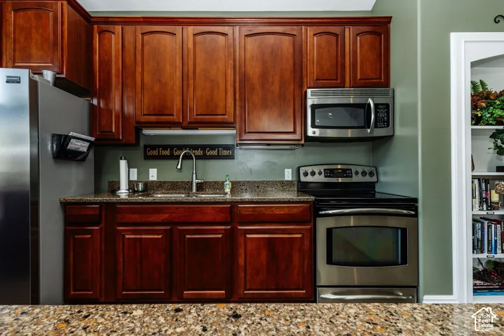 Rich wood cabinetry, stainless steel appliances, granite countertops, and a built-in microwave