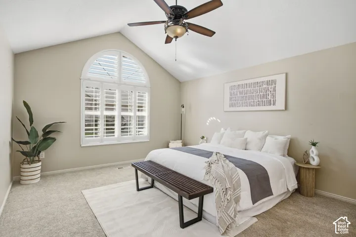 Arched window with plantation shutters, vaulted ceiling, and ceiling fan