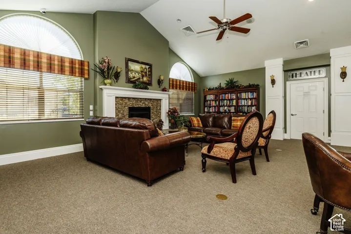 Vaulted ceilings, a built-in fireplace with a stone surround, arched windows, built-in bookshelves, and a ceiling fan