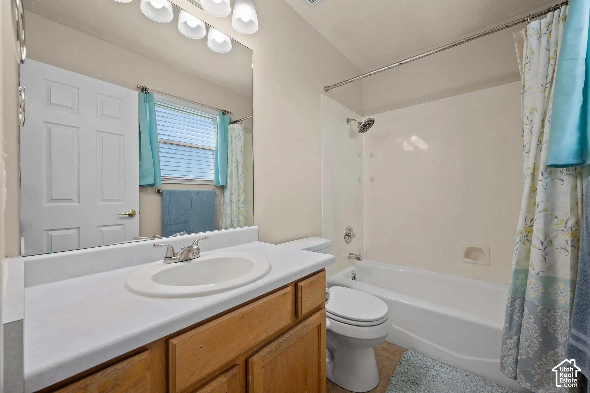 Bathroom featuring a single vanity, wood-finish cabinetry, built-in sink, wall-mounted mirror, and a shower-tub combination