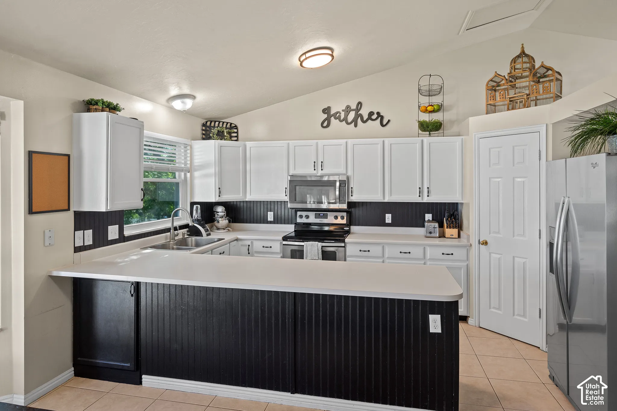 Kitchen featuring white upper cabinetry, a black beadboard backsplash, white countertops, and a stainless steel oven/range and microwave