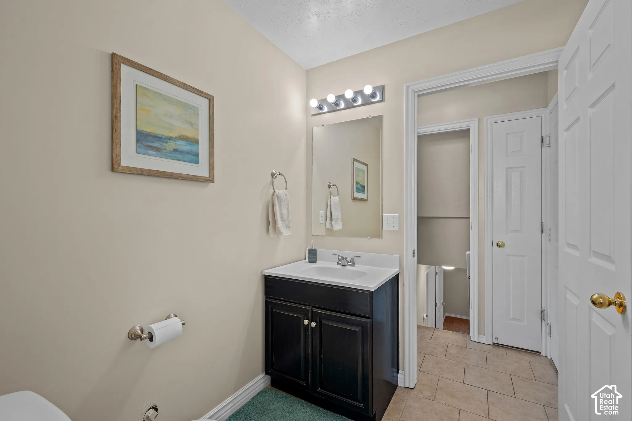Black vanity with white countertop, chrome faucet, and rectangular mirror with five-bulb light fixture