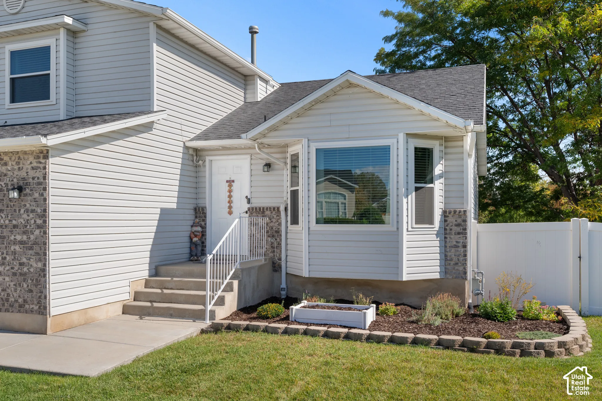 White siding exterior with a dark shingle roof, complemented by stone facade accents