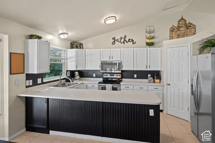 Kitchen featuring white upper cabinetry, a black beadboard backsplash, white countertops, and a stainless steel oven/range and microwave