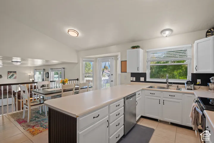 White cabinetry kitchen with light countertops, stainless steel sink, and built-in dishwasher
