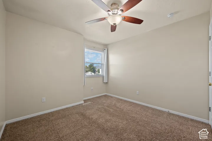 Neutral tone wall finishes, brown carpet flooring, ceiling fan with integrated lighting, window with blinds, and white trim