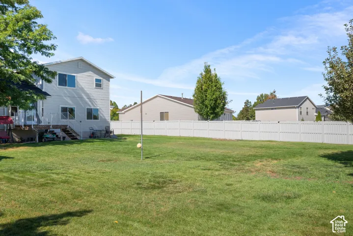 Expansive grassy backyard with a white privacy fence