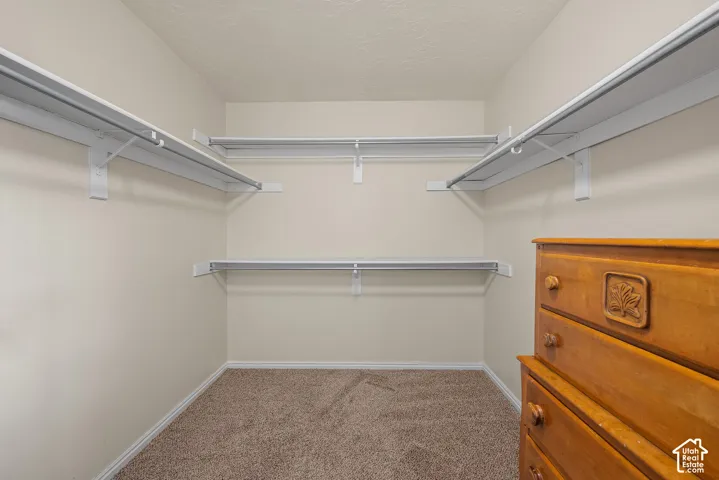 Built-in shelving with hanging rods and neutral tone carpet flooring