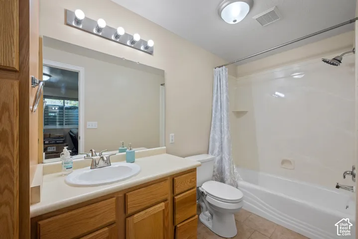 Bathroom featuring a wood-finish vanity with an integrated sink and chrome faucet, a large wall-mounted mirror, and a full shower-tub combination with a chrome showerhead