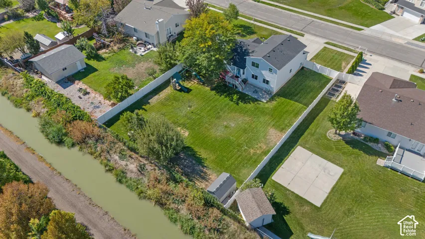 Expansive grassy yard with perimeter fencing, a detached storage shed, and mature trees